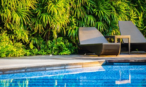 Beautiful outdoor swimming pool with bed deck chair and umbrella in resort for travel and vacation concept