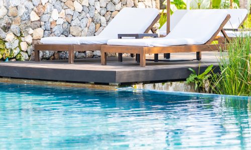 Empty deck chair around outdoor swimming pool in hotel resort for leisure vacation